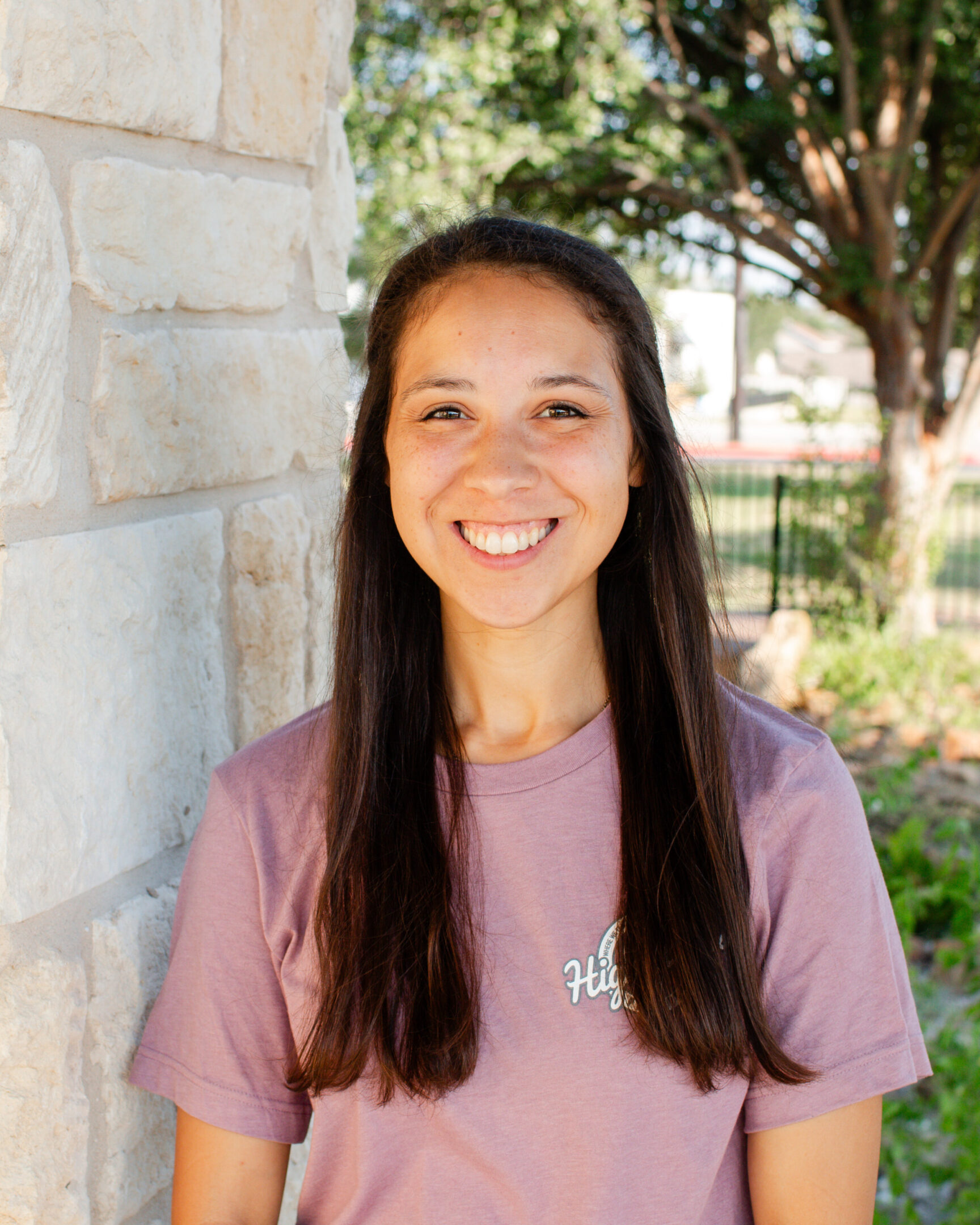 A woman standing in front of a brick wall.