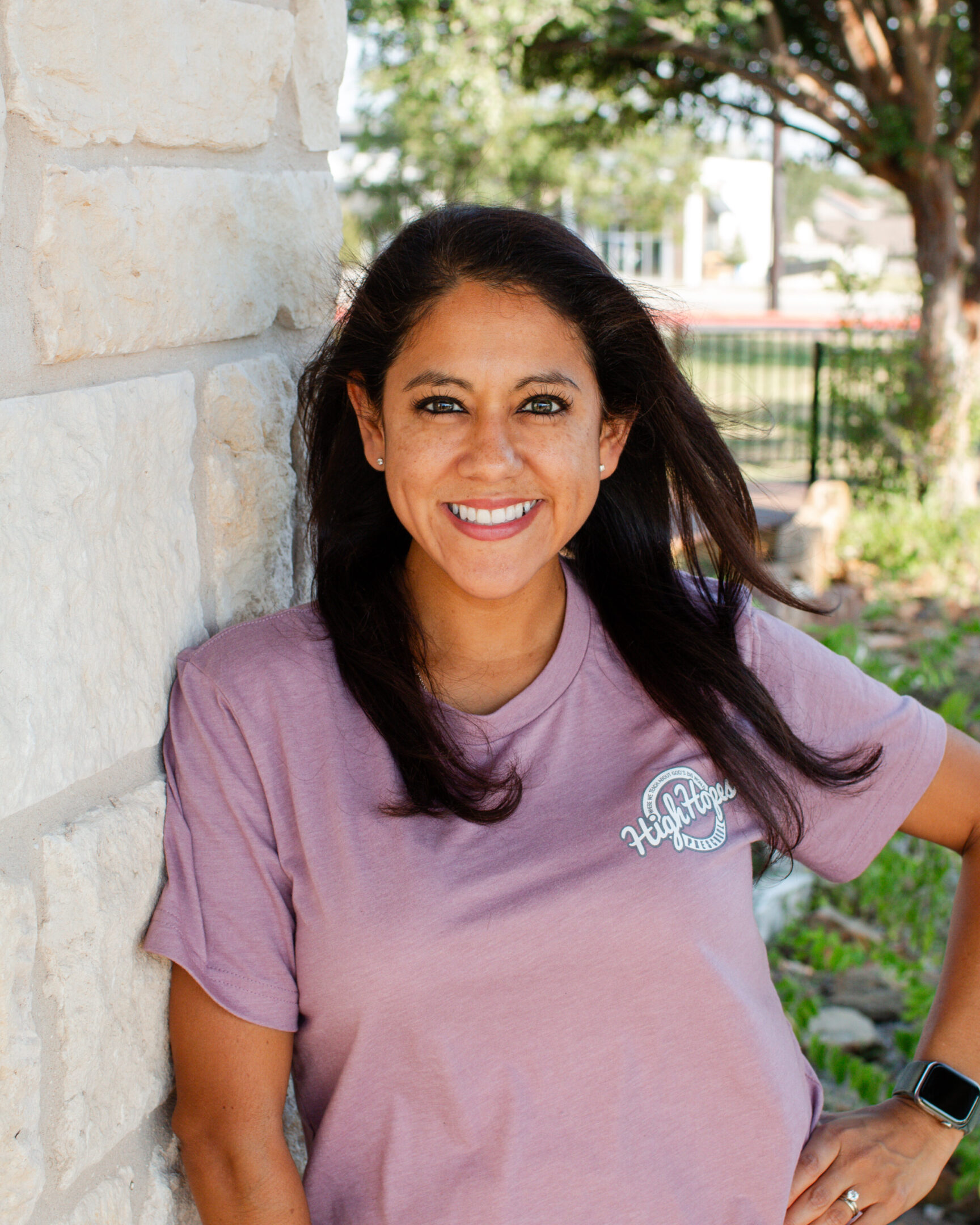 A woman standing next to a brick wall.