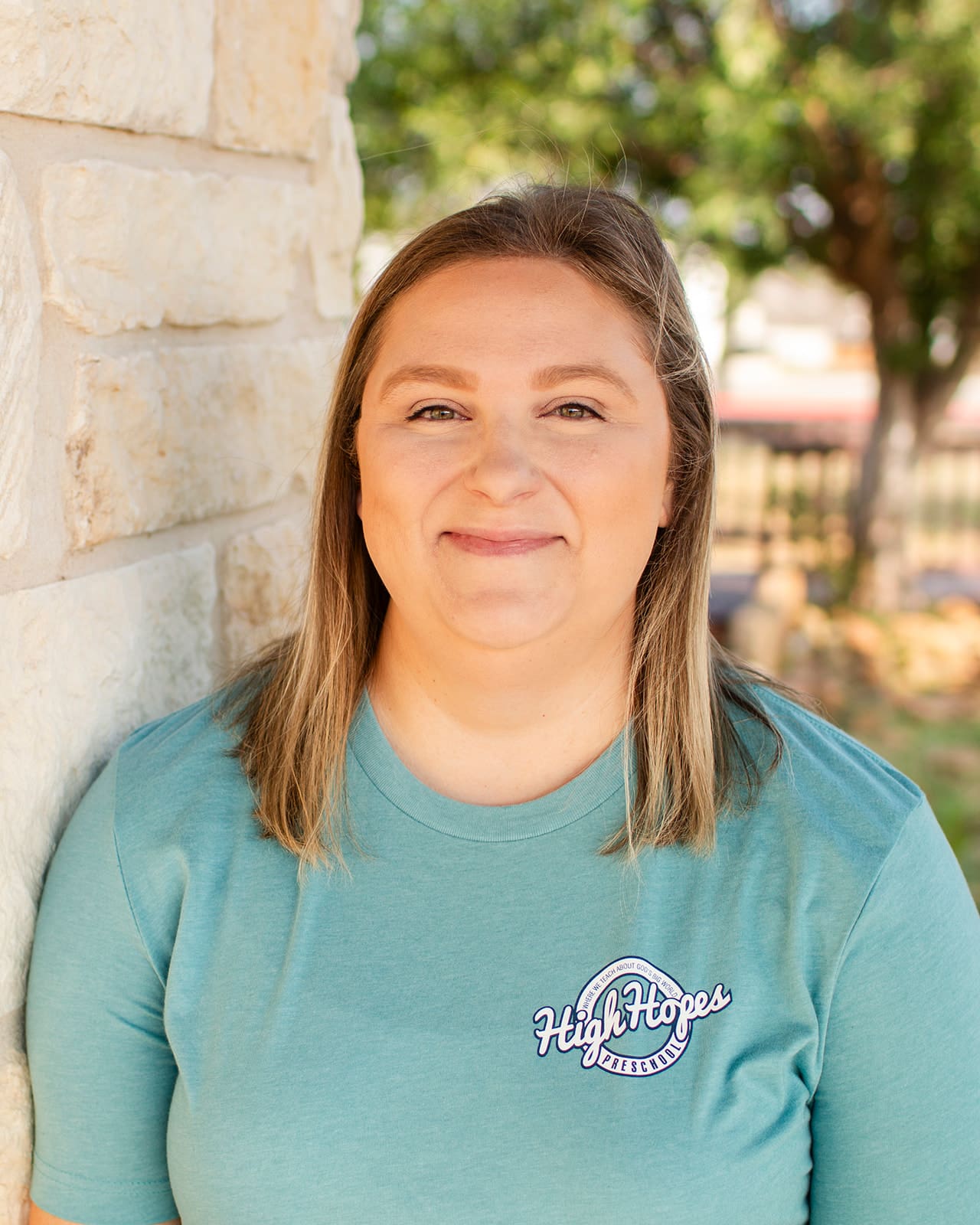 A woman standing in front of a brick wall.