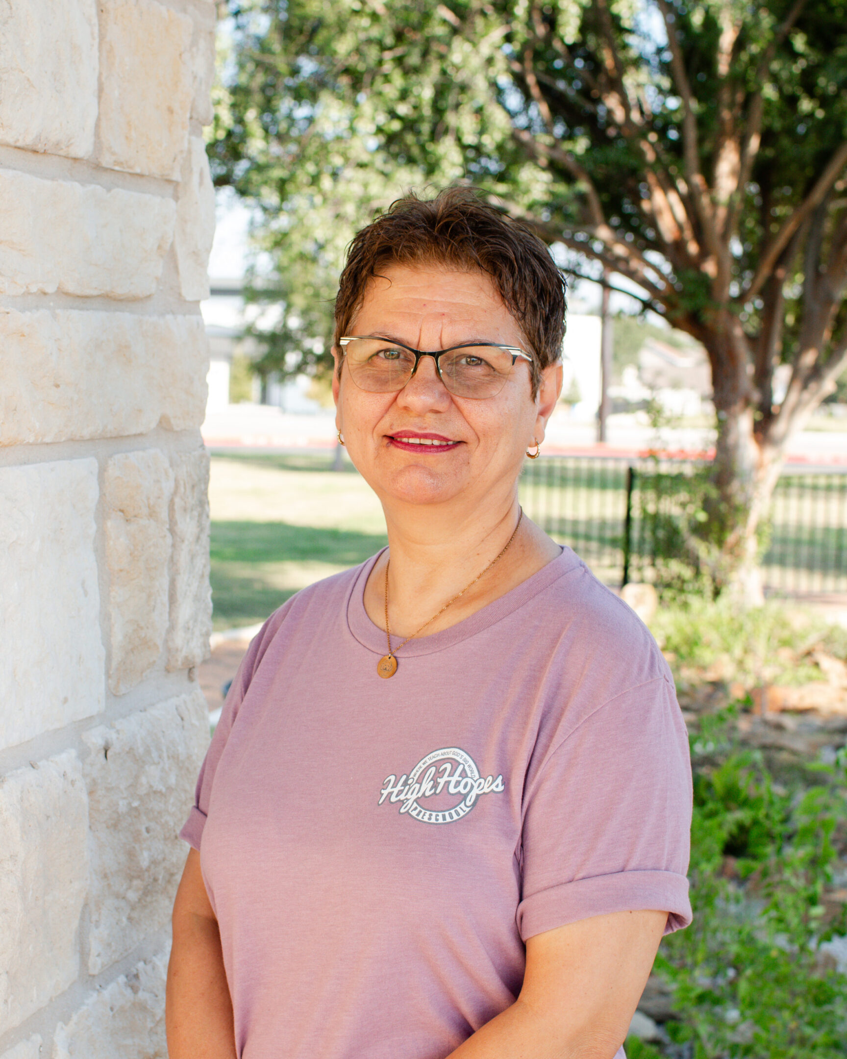 A woman standing in front of a brick wall.