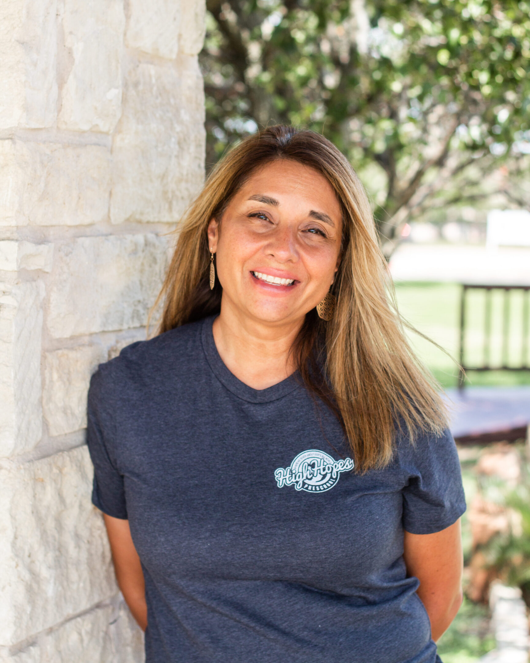 A woman standing next to a wall wearing a blue shirt.