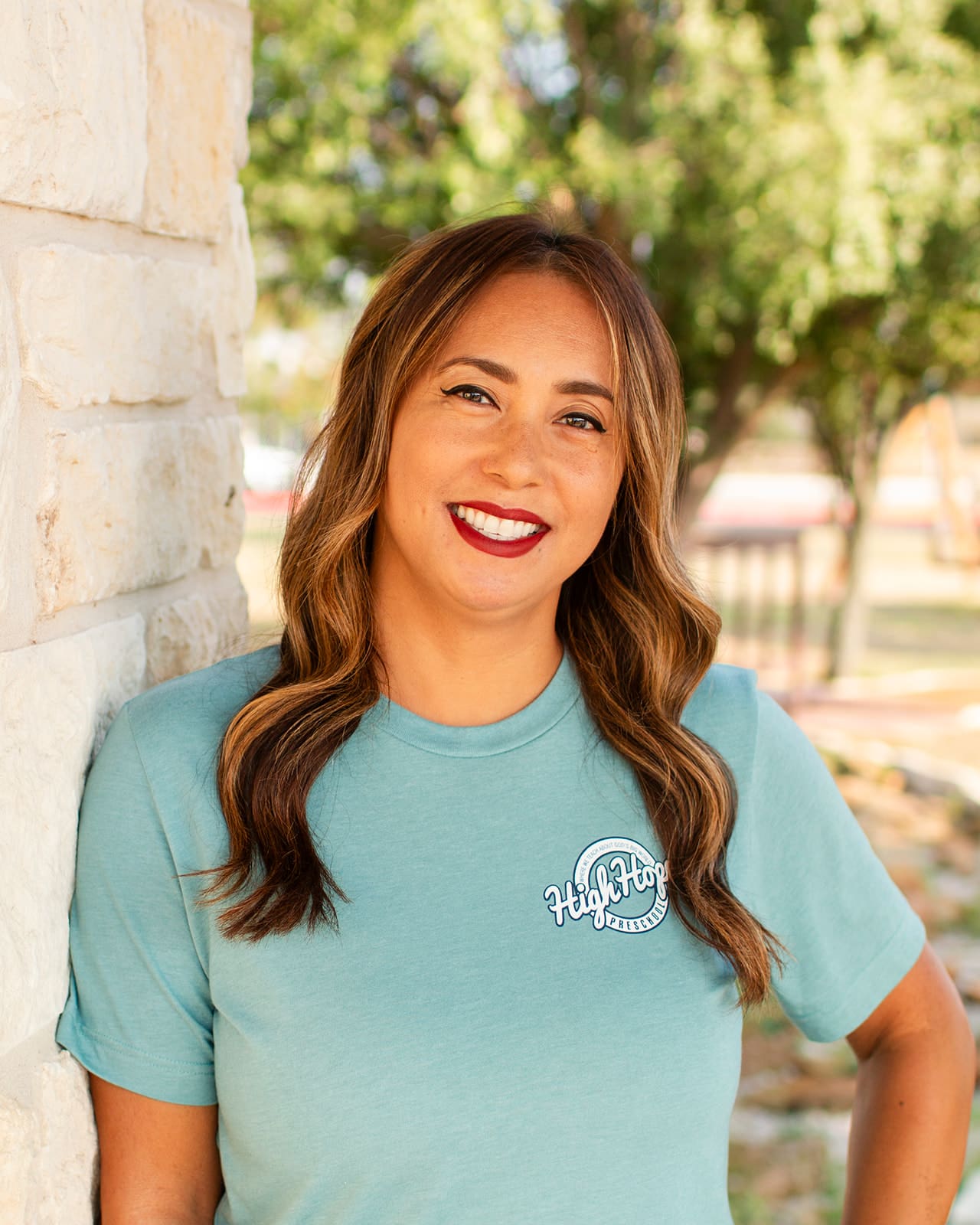 A woman standing next to a brick wall.