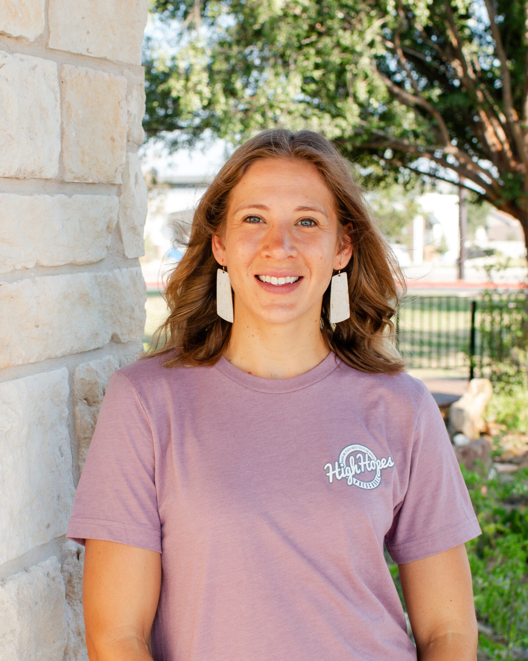 A woman standing in front of a brick wall.