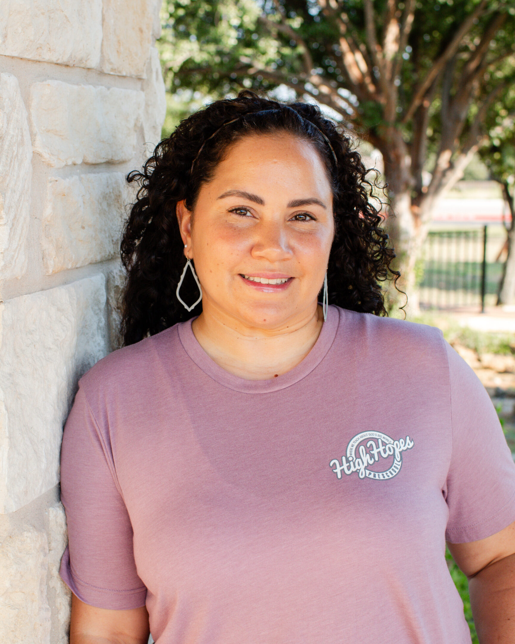 A woman standing next to a brick wall.