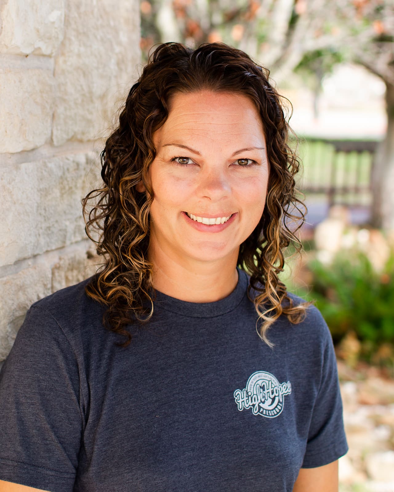 A woman standing next to a brick wall.