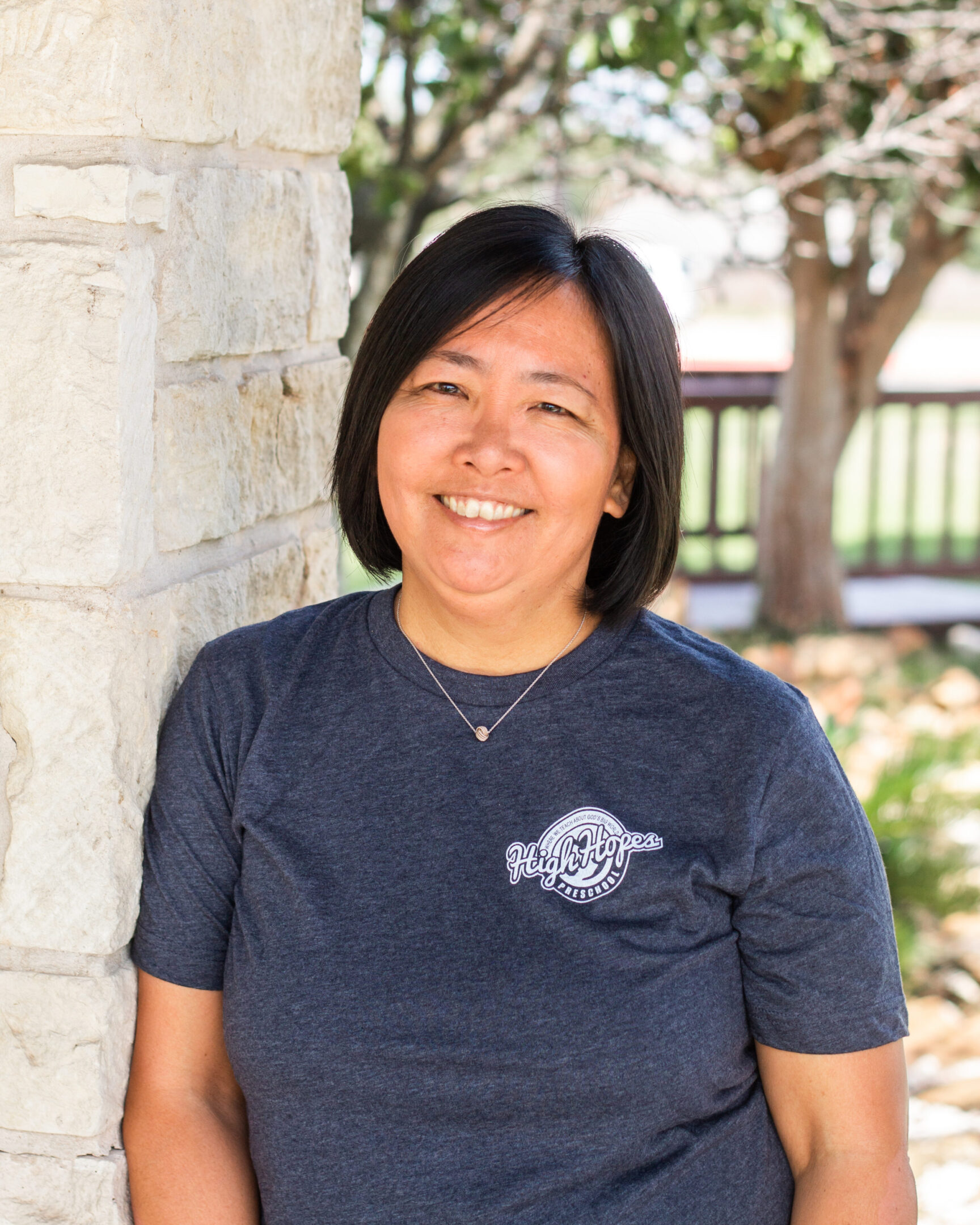 A woman standing next to a stone wall.